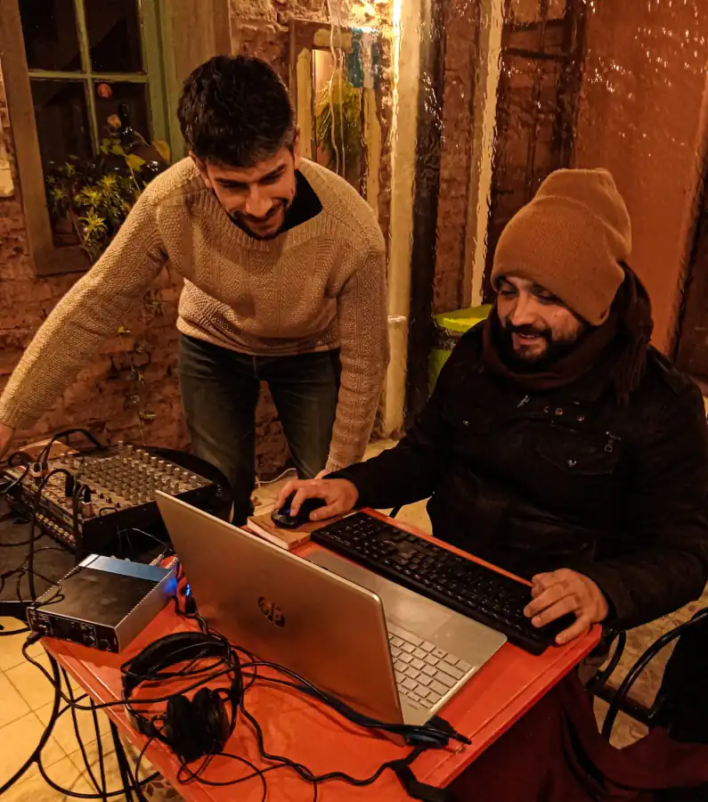 Dos personas trabajando con una computadora y consola de sonido